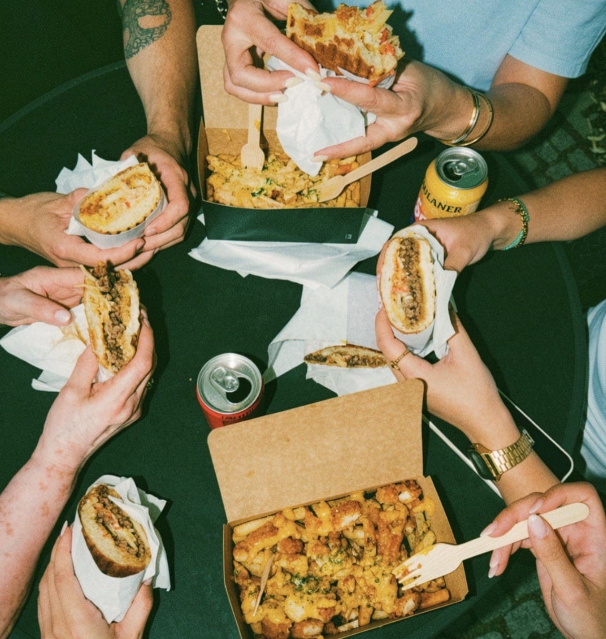 Freunde teilen Sandwiches und Loaded Fries am Tisch