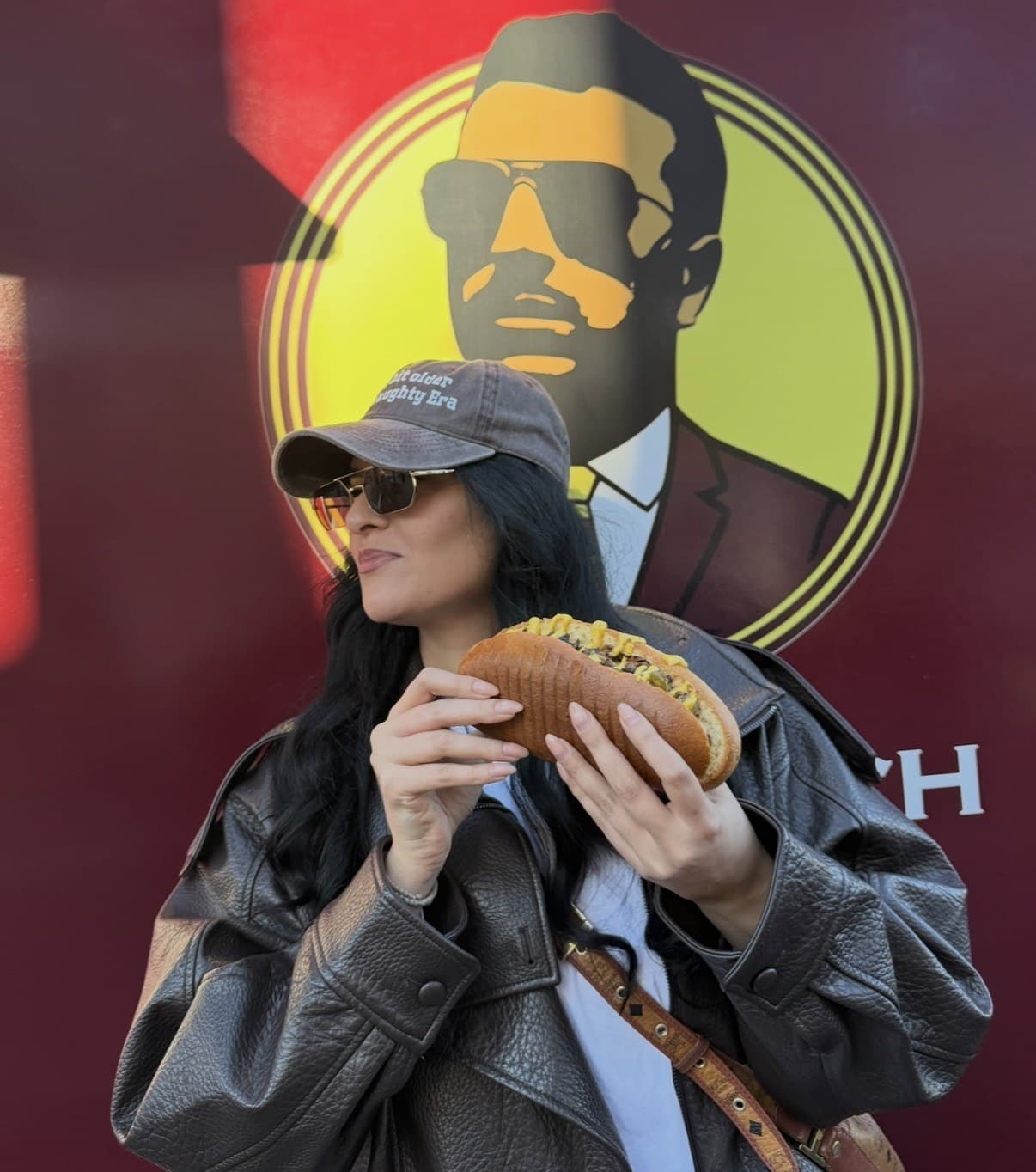 Gast mit Cap und 25cm Sandwich vor dem Pappou’s Logo